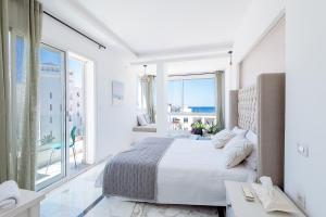 a white bedroom with a bed and a large window at Azur in Bin Rhilouf +16 photos