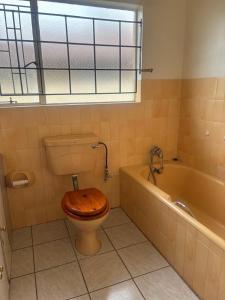 a bathroom with a toilet with a wooden seat at Ruros Guest House in Kempton Park +7 photos