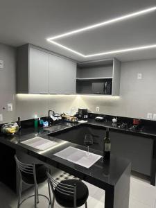 a kitchen with a counter with a sink and chairs at Quarto Individual e Privativo - Apt moderno compartilhado com o Hoster - Boa Viagem in Recife