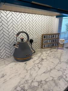ein Teekessel auf einer Theke neben einem Schild in der Unterkunft Salcombe Hideaway in Salcombe