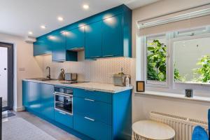 eine Küche mit blauen Schränken und einem Fenster in der Unterkunft Salcombe Hideaway in Salcombe