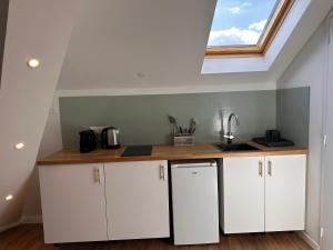 eine Küche mit weißen Schränken und einem Dachfenster in der Unterkunft Tendance & Confort à Perigueux in Périgueux