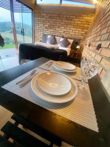 a table with plates and glasses on it with a couch at Pousada Chalé privativa mirante do sol in Socorro +34 photos