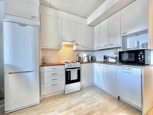 a kitchen with white appliances and white cabinets at Cozy flat in Suurpelto in Espoo