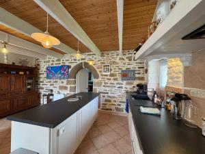 a kitchen with a black counter and a stone wall at Ty Guillerm - Maison bretonne entre terre et mer in Plounévez-Lochrist +25 photos