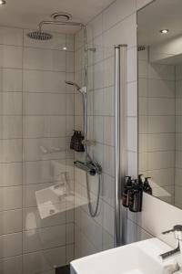 a shower with a glass door next to a sink at Home Hotel Slottsparken in Linköping