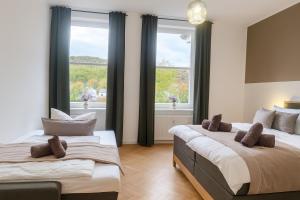 two beds in a room with two windows at Exklusive Fewos - 6 SZ - 14 P - 2 Küchen - 4 Bäder - Mitten in Deutschland - Bahnhof & Altstadt fußläufig in Bad Sooden-Allendorf