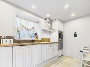 une cuisine avec des armoires blanches et une fenêtre dans l'établissement The Old Pen Cottage, à Leafield