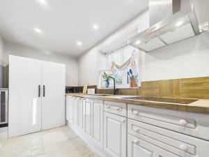 a kitchen with white cabinets and a sink at Cotswolds Cottage with Hot tub in Leafield