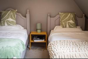 une chambre avec deux lits et une table avec une lampe dans l'établissement The Old Pen Cottage, à Leafield