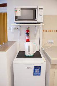 a microwave and a coffee maker on top of a refrigerator at Cabañas Mi Cata Hermosa - Catamarca Capital in San Fernando del Valle de Catamarca