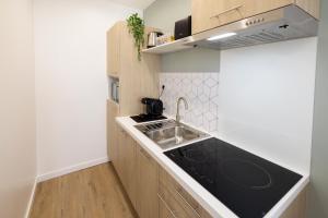 Una pequeña cocina con fregadero y estufa. en Le Vert Olivier- Studio tout confort, en Montluçon