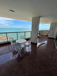 a balcony with a table and chairs and the ocean at Varandão com vista na Praia dos Namorados in Guarapari