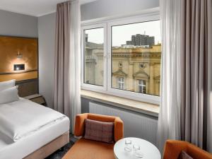a hotel room with a bed and a large window at Mercure Hotel Dortmund Centrum in Dortmund