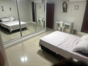 a bedroom with two beds and a table and mirrors at Casa Confortável in Belém
