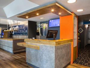 a bar in a restaurant with an orange and gray counter at ibis budget Marne la Vallée Chelles in Chelles
