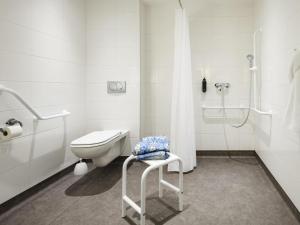 a white bathroom with a toilet and a shower at ibis budget Clermont Ferrand Sud in Aubière +36 photos