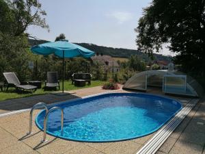 a swimming pool with an umbrella and a tent at Penzion Ječmínek in Červená Voda