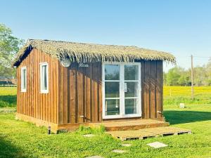 a small hut with a grass roof and a window at Chalet en bois in Labatut +1 photo