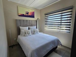 a bedroom with a large white bed with a window at Nat's Villa in Midrand +14 photos