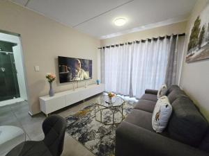 a living room with a couch and a tv at Nat's Villa in Midrand