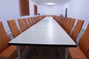 une salle de conférence vide avec une grande table et des chaises dans l'établissement Hotel Romantik, à Bălăuşeri