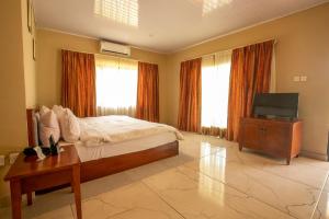 a bedroom with a bed and a television and a table at Busua Beach Resort in Busua
