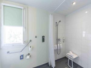 a bathroom with a shower and a toilet and a window at ibis budget Montpellier Sud Près d'Arènes in Montpellier +45 photos