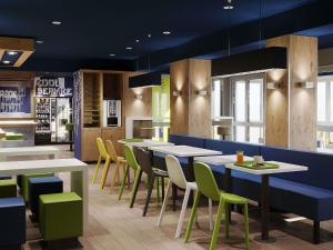 ein Restaurant mit weißen Tischen und grünen Stühlen in der Unterkunft ibis budget Poitiers Nord Futuroscope in Chasseneuil-du-Poitou