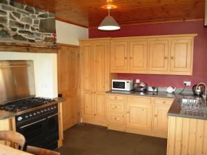 una cocina con armarios de madera y estufa negra en Overwater Lodge, en Bassenthwaite Lake