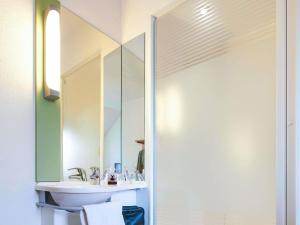 a bathroom with a sink and a mirror at ibis budget Tours Nord in Tours +49 photos