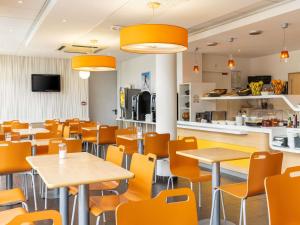 a restaurant with tables and chairs and a kitchen at ibis budget Tours Nord in Tours