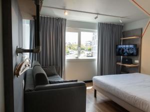 a bedroom with a bed and a couch and a window at Ibis Budget Saint Malo Centre in Saint Malo +112 photos