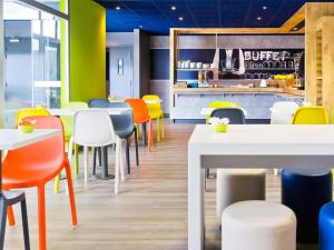 サン・マロにあるIbis Budget Saint Malo Centreの明るい色のテーブルと椅子が備わるレストラン