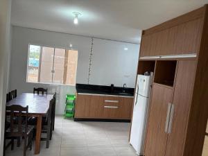 a kitchen with a table and a white refrigerator at apartamento lindo com 2 quartos in Itapoa