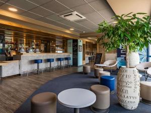 a lobby with tables and chairs and a plant at ibis budget Marne la Vallée Pontault Combault in Pontault-Combault