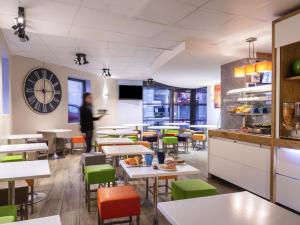 a restaurant with tables and chairs and a person in the background at ibis budget Cannes Centre Ville in Cannes