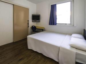 een slaapkamer met een groot wit bed en een raam bij ibis budget Rio de Janeiro Centro in Rio de Janeiro