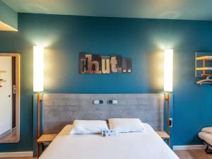 a bedroom with a large bed with two lights on it at ibis budget Pertuis Portes du Luberon in Pertuis +50 photos