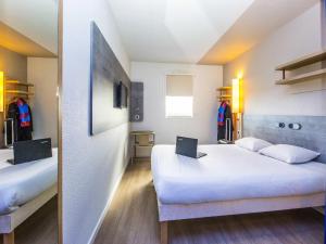 a bedroom with two beds with a laptop on it at Ibis Budget Marmande in Marmande