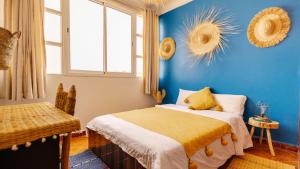 a bedroom with a bed and a blue wall at Freebird Surfcamp Morocco in Agadir +48 photos