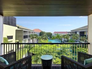 a balcony with chairs and a view of a pool at Mercure Bali Legian in Legian