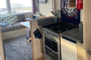 a kitchen with a stove top oven next to a living room at Cabin - Sleeps 4 - Pets Ok - Balcony - Parking in Watchet +2 photos