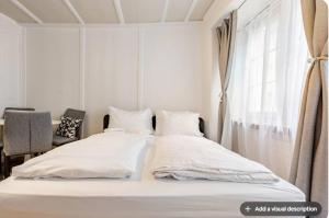 une chambre blanche avec deux lits et une fenêtre dans l'établissement City Center Apt With AC in Zurich Old Town, à Zurich 1 autre photo