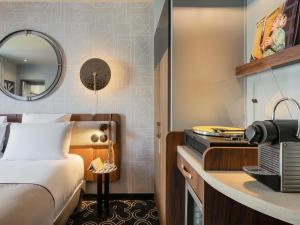 une chambre d'hôtel avec un lit et un miroir dans l'établissement Mercure Paris Opera Grands Boulevards, à Paris