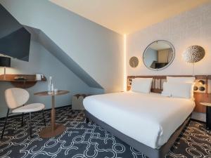 une chambre d'hôtel avec un grand lit et une table dans l'établissement Mercure Paris Opera Grands Boulevards, à Paris