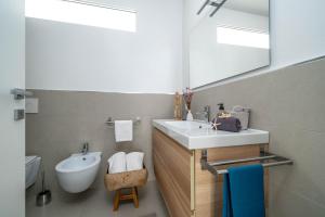 ein Badezimmer mit Waschbecken, Toilette und Spiegel in der Unterkunft Casa Bilum in Sommacampagna