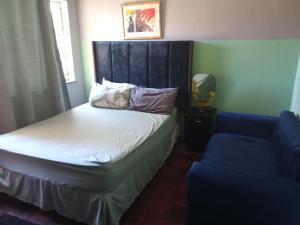 a bedroom with a bed with a headboard and a blue couch at ATHOME BELLVILLE Chrismar in Cape Town
