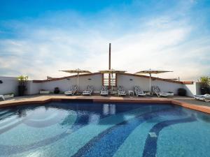 a swimming pool with chairs and umbrellas on a hotel at Signature Hotel Al Barsha in Dubai