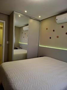 a bedroom with a white bed and a mirror at NOVO e DECORADO no Centro de Canela! in Canela